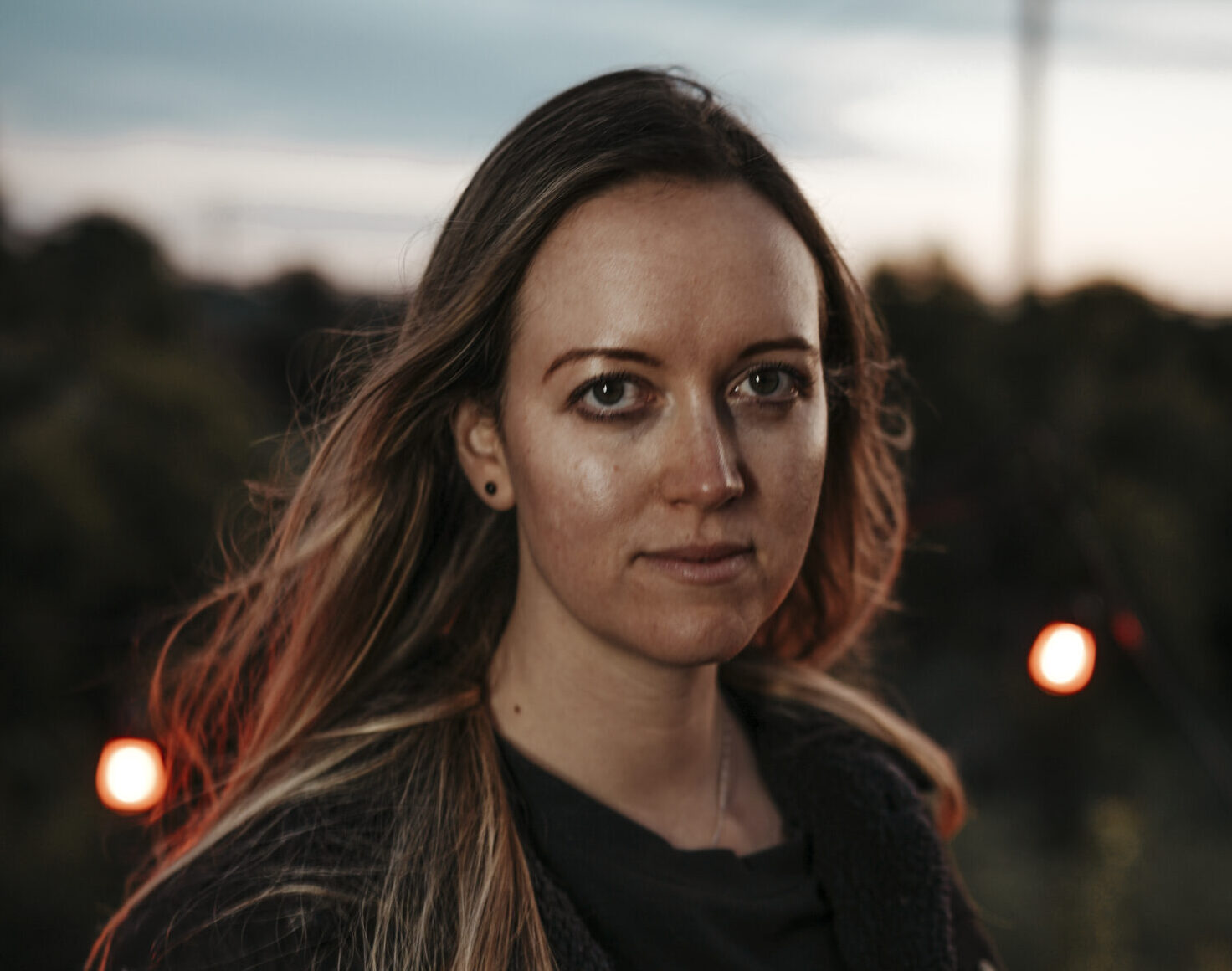 Image of Alenka the founder standing outside during sunset with red back lighting